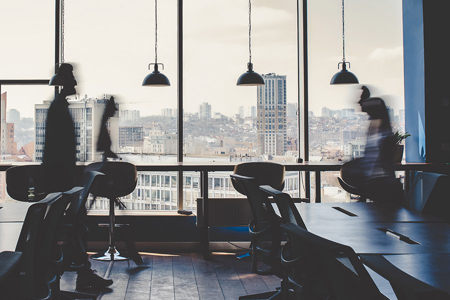 About Our Agency - View of Modern Office with Business Men and Women Walking and Blurred in the Foreground with Forida City in the Background