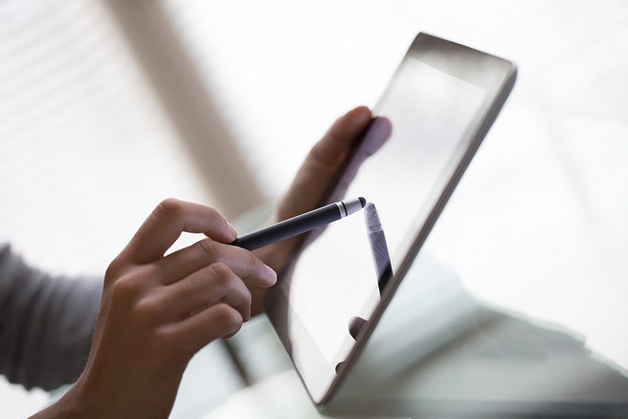 Client Center - Closeup of Woman's Hands Using a Stylus and Tablet While Accessing Important Insurance Account Information