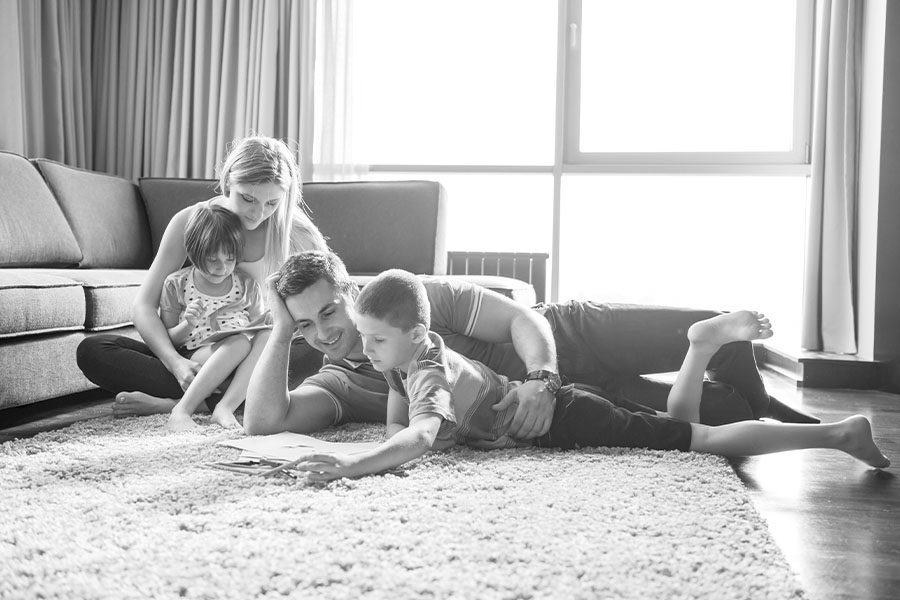 Home FAQs - Grayscale View of Young Couple Spending Time With Kids at Home on the Sofa